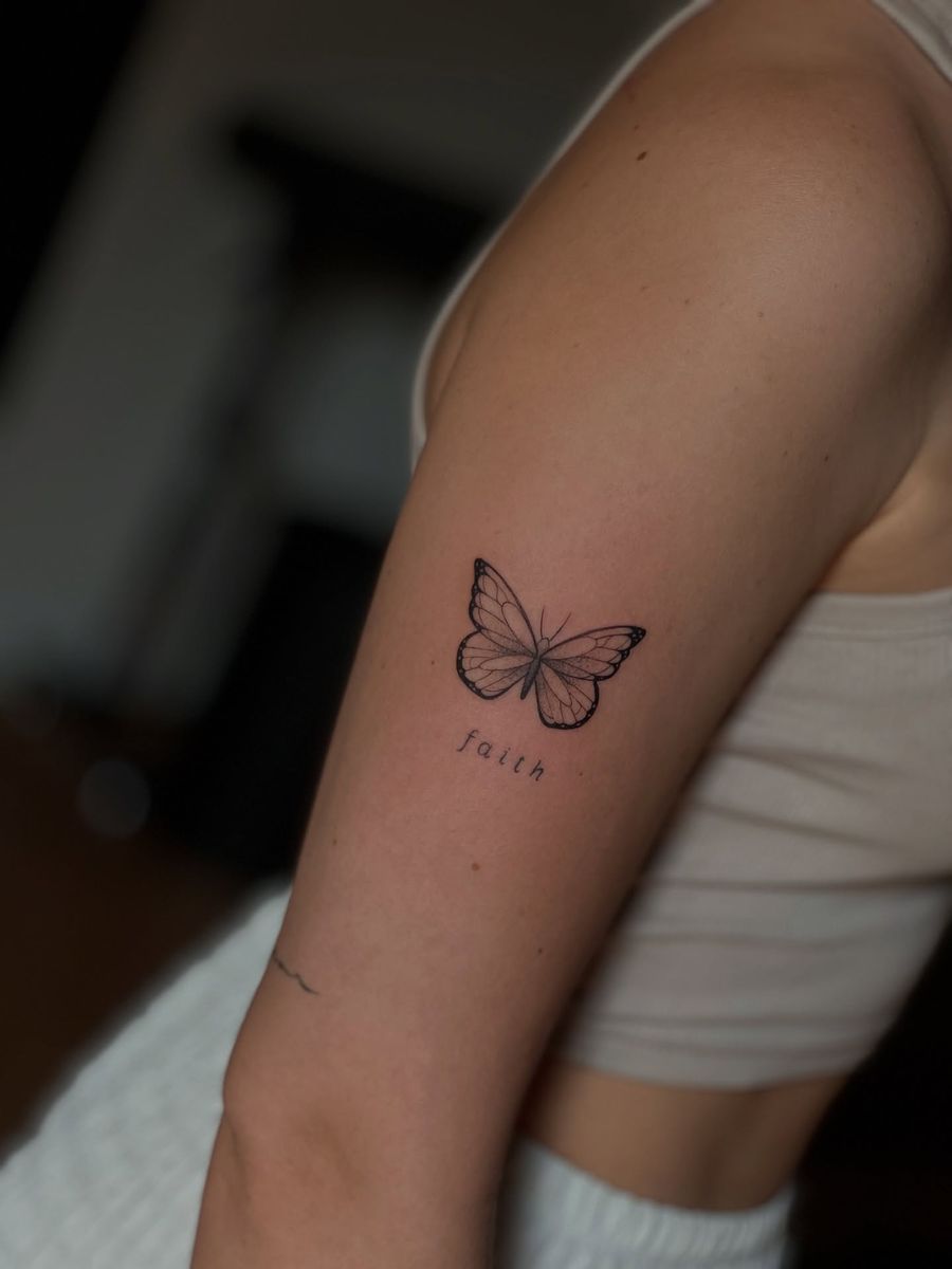 Kleiner Fineline-Schmetterling mit Schriftzug am Oberarm, gestochen von Bene
