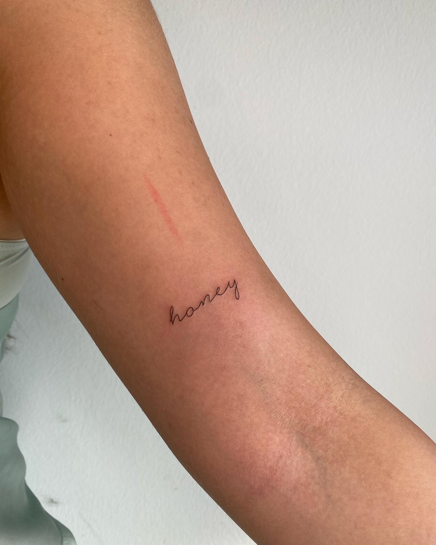 Feiner Schriftzug „honey“ am Unterarm, gestochen von Max